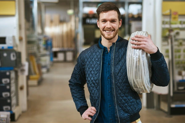 Jovem eletricista sorridente segurando um rolo de cabo elétrico, representando confiança e qualidade nos produtos oferecidos pela Condvolt para projetos industriais e comerciais.