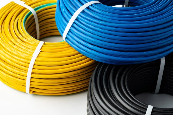 Três rolos de fios elétricos coloridos sobre uma superfície branca, representando a qualidade e a importância da certificação em projetos industriais e comerciais.